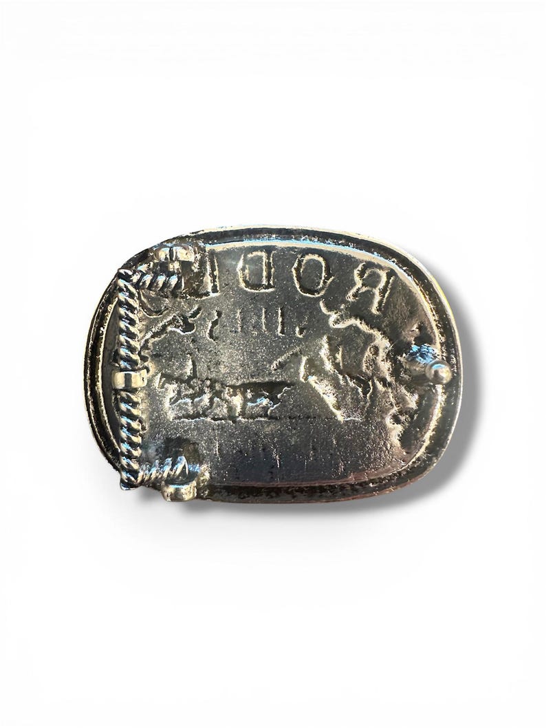May include: Silver-toned metal belt buckle with the word "ROD" in raised letters. The buckle has a rectangular shape with rounded edges and a rope-like border. A detailed image of a horse is visible.