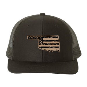 May include: A dark grey trucker cap with a distressed Oklahoma state flag design. The flag design is tan, with stars and stripes. The cap has a mesh back and a curved peak.