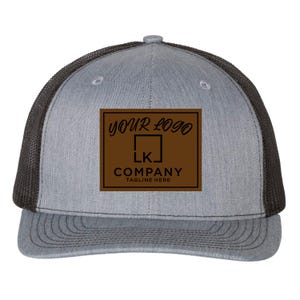 May include: A grey and black trucker hat with a brown patch that says "YOUR LOGO" and "COMPANY TAGLINE HERE" with a stylised "LK" inside a square.