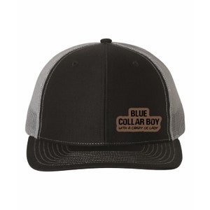 May include: A black and gray trucker hat with a brown patch that reads "BLUE COLLAR BOY WITH A CRAZY OL LADY".