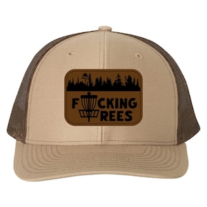 May include: A tan and brown trucker hat with a mesh back. The front features a brown patch with a disc golf basket graphic and the words "F*CKING REES" in white.