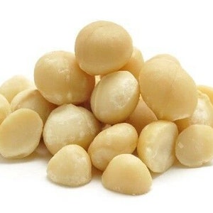 Può includere: Una vista ravvicinata di un mucchio di noci di macadamia, un tipo di noce commestibile. Le noci sono di colore marrone chiaro e hanno una superficie liscia e leggermente ruvida.