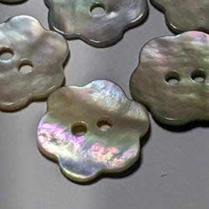 May include: A set of iridescent white mother of pearl buttons in a flower shape with two holes.