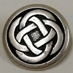 May include: A silver Celtic knot design button with a black background. The knot is a traditional symbol of eternity and interconnectedness.