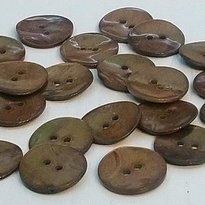 May include: A collection of 20 brown and iridescent shell buttons with two holes each. The buttons are oval shaped and have a mottled appearance.