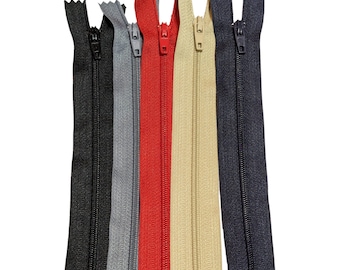 Könnte beinhalten: Fünf Reißverschlüsse in verschiedenen Farben: Schwarz, Grau, Rot, Beige und Marineblau. Die Reißverschlüsse sind alle gleich groß und im gleichen Stil.