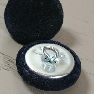 May include: Two black velvet buttons with a silver shank. The button on the right has a silver back with a loop.
