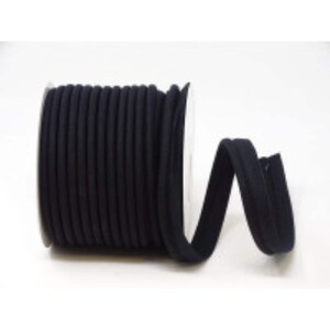 May include: A spool of black elastic cord, a type of fabric trim, is wound around a white cardboard core. The cord is folded and laid out in a loose loop to the right of the spool.
