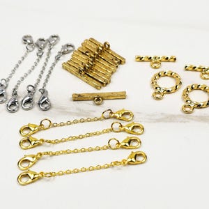 May include: An assortment of jewelry findings, including gold and silver-toned lobster clasps, chain extenders, and toggle clasps. The gold pieces have a twisted rope design. Ideal for jewelry making and crafting.