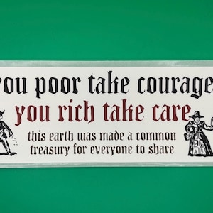 May include: A rectangular white sticker with black and burgundy text that reads "you poor take courage, you rich take care, this earth was made a common treasury for everyone to share." Two black and white illustrations of figures are on either side of the text.