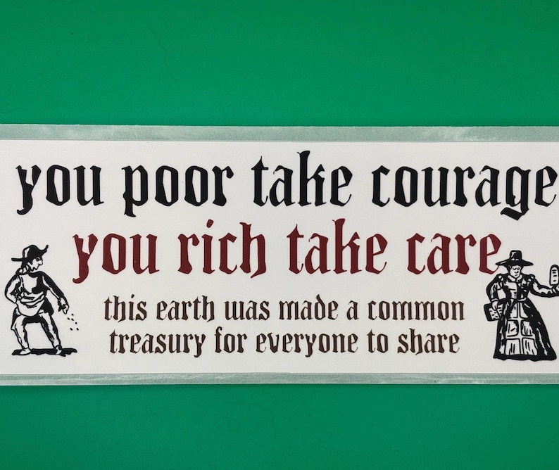 May include: A rectangular sign with a white background and black and maroon text. The text reads "you poor take courage, you rich take care, this earth was made a common treasury for everyone to share." Two cartoon figures are on either side of the text.