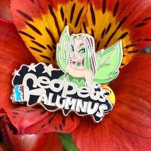 Könnte beinhalten: Eine grüne und schwarze Emaille-Anstecknadel mit einer Fee mit grünen Flügeln und dem Text "Neopets Alumni".