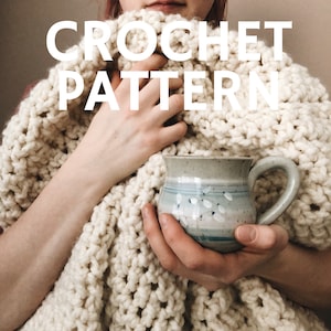 Może przedstawiać: Osoba trzyma biały dzianinowy koc i jasnoniebieski i szary ceramiczny kubek z kwiatowym wzorem. Tekst "CROCHET PATTERN" jest napisany białymi literami na jasnobrązowym tle.