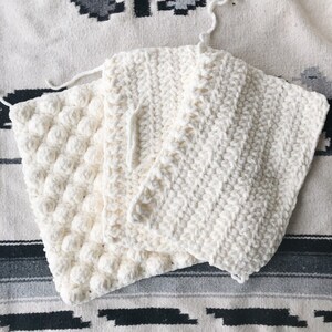 May include: Three white crocheted squares with different stitch patterns. The squares are stacked on top of each other.