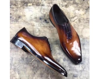 May include: Two pairs of brown leather lace-up shoes with a pointed toe. The shoes have a glossy finish and a dark brown sole.