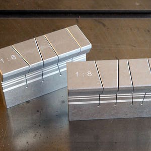 Peut inclure: Deux guides de coupe en métal argenté avec des marquages pour les rapports 1:6 et 1:8. Les guides sont conçues pour couper du bois ou d'autres matériaux en sections égales.