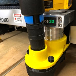 May include: A yellow and black 3D printer attachment with a blue and black vacuum hose. The attachment has a black brush and a black knob. The text "ide 3D" is visible on the attachment.