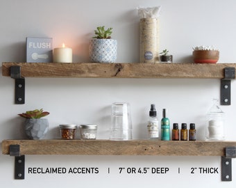 May include: Two rustic wooden shelves with black metal brackets, displaying decorative items like plants, candles, and jars. The shelves are 7 inches or 4.5 inches deep and 2 inches thick. The text "RECLAIMED ACCENTS" is visible.