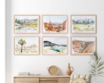 May include: Six framed watercolor paintings of different landscapes, including mountains, canyons, and a lake. The paintings are hung on a white wall above a wooden dresser with a woven rug on the floor.