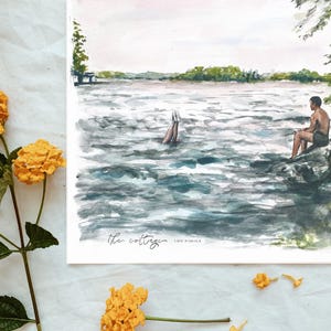 May include: Watercolor painting of a lake scene with a person sitting on a rock and another person diving into the water. The painting is titled "the cottage". Yellow flowers are in the foreground.