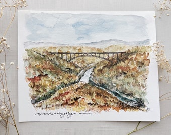 May include: Watercolor painting of a bridge over a river gorge. The bridge is brown and the river is blue. The gorge is green and brown. The painting is signed "New River Gorge National Park".