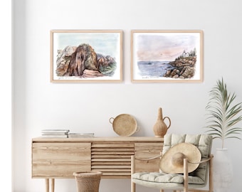 May include: Two framed watercolor paintings of landscapes. The left painting shows a rocky mountain scene with a green forest in the background. The right painting shows a coastal scene with a lighthouse and a sailboat in the distance.