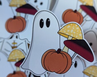 Könnte beinhalten: Ein weißer Geist, der einen rot-weißen Pilz mit gelben Punkten und einen kleinen orangefarbenen Kürbis hält. Der Geist hat zwei schwarze Augen.