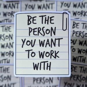 May include: A white sticker with a yellow lined background and a paperclip icon. The sticker has black text that reads "Be the person you want to work with."