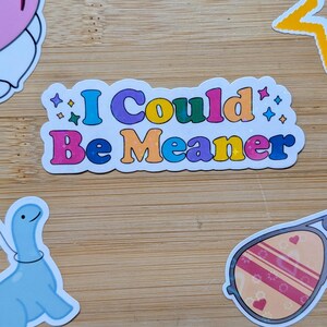 May include: A rectangular sticker with a white border featuring the text I Could Be Meaner in colorful, bold, rounded letters. The design includes small star-shaped accents in various colors scattered around the text on a white background.