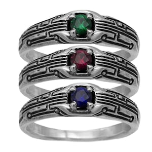以下が含まれることがあります： 回路基板のデザインが施された銀の指輪が3つ。指輪には緑、赤、青の異なる色の宝石がセットされています。