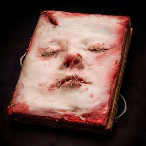 Front view of human skin face book, handmade dark art book with sculpted human face and realistic skin-like texture
