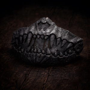Half mask with fangs displayed as dark art object, handmade lightweight mask shown as sculptural piece