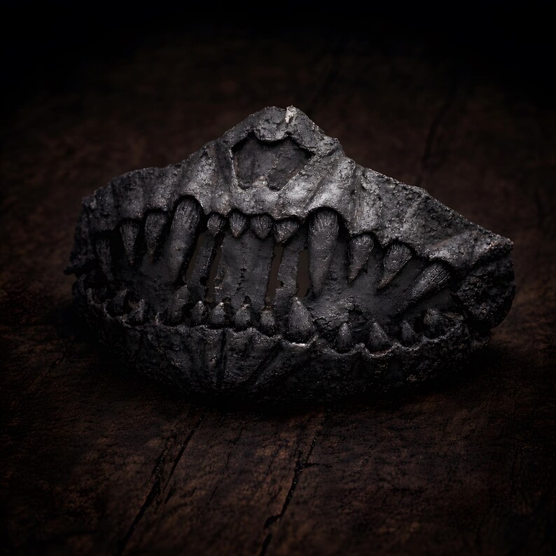 Half mask with fangs displayed as dark art object, handmade lightweight mask shown as sculptural piece