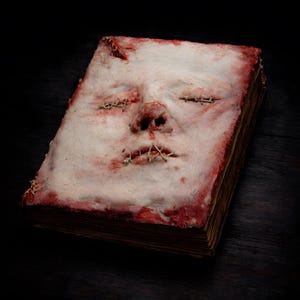 Human skin face book displayed as dark art object, handmade macabre book for collectors and gothic interiors