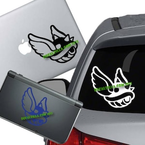 May include: A white sticker of a winged, spiky shell with a black outline. The sticker is shown on a laptop, a Nintendo 3DS, and a car. The sticker is available in a variety of colors.