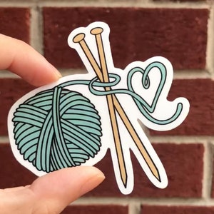 May include: A sticker featuring a ball of teal yarn with two wooden knitting needles and a heart-shaped loop of yarn.