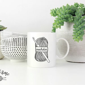 May include: White ceramic mug with a black and white illustration of a ball of yarn and crochet hook. The text "crocheter" is written on the mug.
