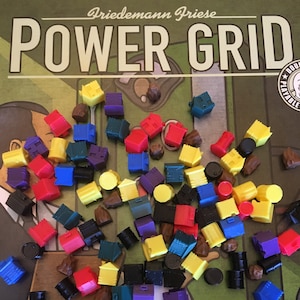 May include: A collection of colorful game pieces for the board game Power Grid by Friedemann Friese. The pieces include houses, power plants, and resource tokens in various colors, including red, blue, yellow, green, and purple.