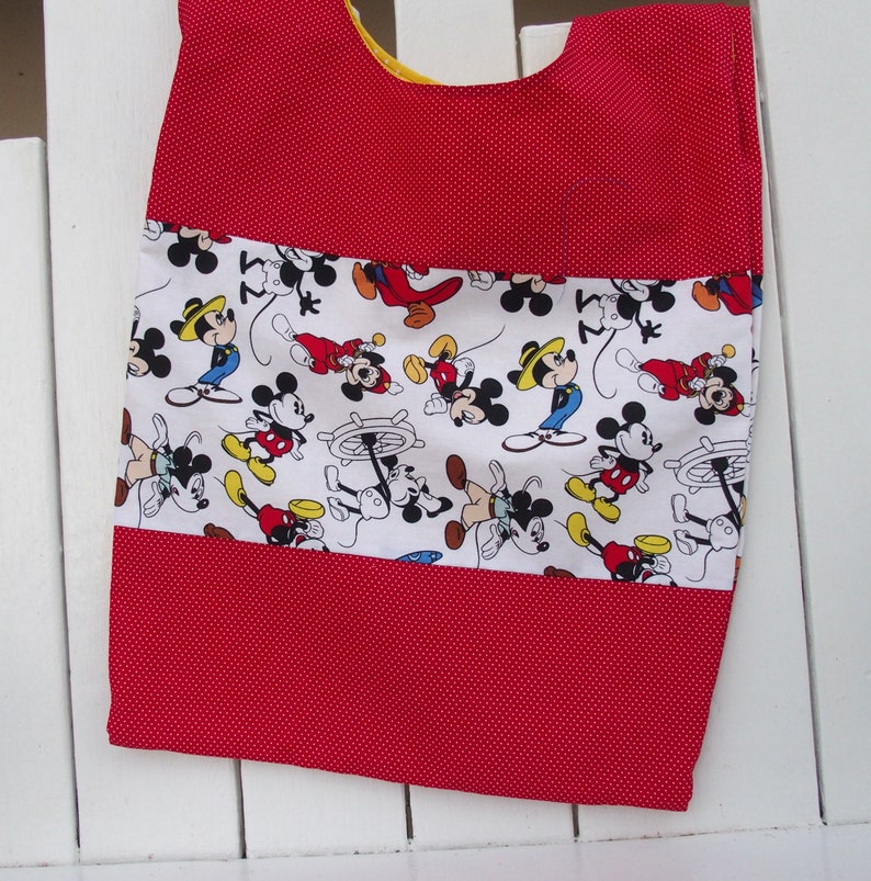 May include: Red and white fabric with a Mickey Mouse print. The fabric has a red polka dot pattern and a white stripe with Mickey Mouse characters.