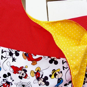 May include: A red and yellow fabric tote bag with a white background featuring a repeating pattern of Mickey Mouse characters. The bag has a polka dot pattern on the red and yellow fabric.