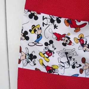 May include: White fabric with a red polka dot pattern. The fabric has a white panel with a repeating pattern of Mickey Mouse characters in various poses. The characters are in black, red, yellow, and blue.