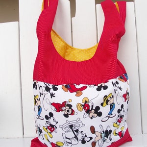 May include: Red and yellow fabric tote bag with white polka dots. The bag features a white fabric panel with a repeating pattern of Mickey Mouse characters.