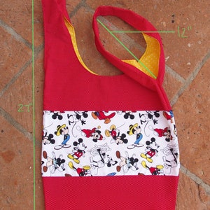 May include: Red and yellow fabric tote bag with a white panel featuring a Mickey Mouse print. The bag measures 12 inches wide by 21 inches tall and 13 inches long.