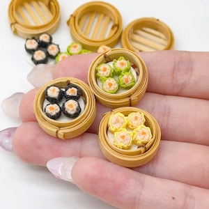 May include: Miniature bamboo steamer baskets containing small dumplings in various colors including black, green, and yellow. Each dumpling features a light-colored center. The set includes several empty bamboo baskets and additional loose dumplings.