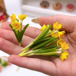 Puede incluir: Un ramo de flores de narciso amarillas con tallos verdes. Las flores están hechas de arcilla polimérica y son perfectas para casas de muñecas en miniatura u otros proyectos de manualidades.