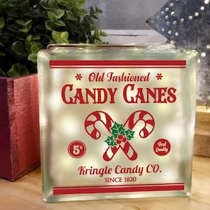 May include: A frosted glass block with a red and white candy cane design. The text reads "Old Fashioned Candy Canes" and "Kringle Candy Co. Since 1820".