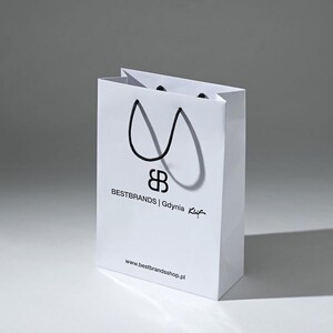 May include: White paper shopping bag with black handles and the text "BESTBRANDS | Gdynia Kuf" and "www.bestbrandsshop.pl" printed on the front.