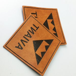 May include: Two brown leather patches with black stitching and a black triangle design. The text "TWIN" is printed on one patch and "TWIN" is printed on the other patch.