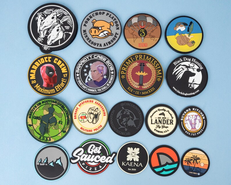 May include: A collection of round patches with various designs. Some feature cartoon characters, military emblems, and text like "Maximum Effort" and "Get Sauced Pizza." The patches are in various colors, including black, white, red, and blue.