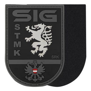 May include: A black and gray patch with the text "SIG" at the top and "STMK" vertically on the left. A white lion and a gray eagle with a red and white shield are featured. The text "SRK" is at the bottom.